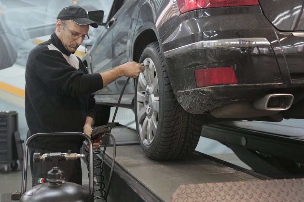 An image of a mechanic putting air in a car's tyres