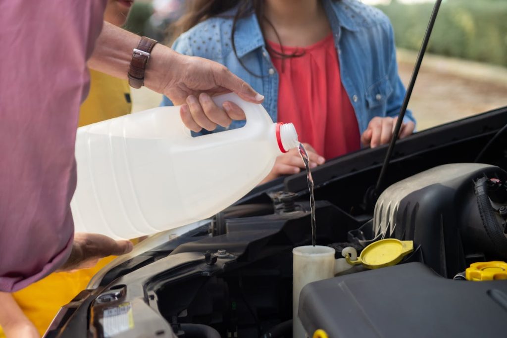 Image of a man pouring fluid into his car