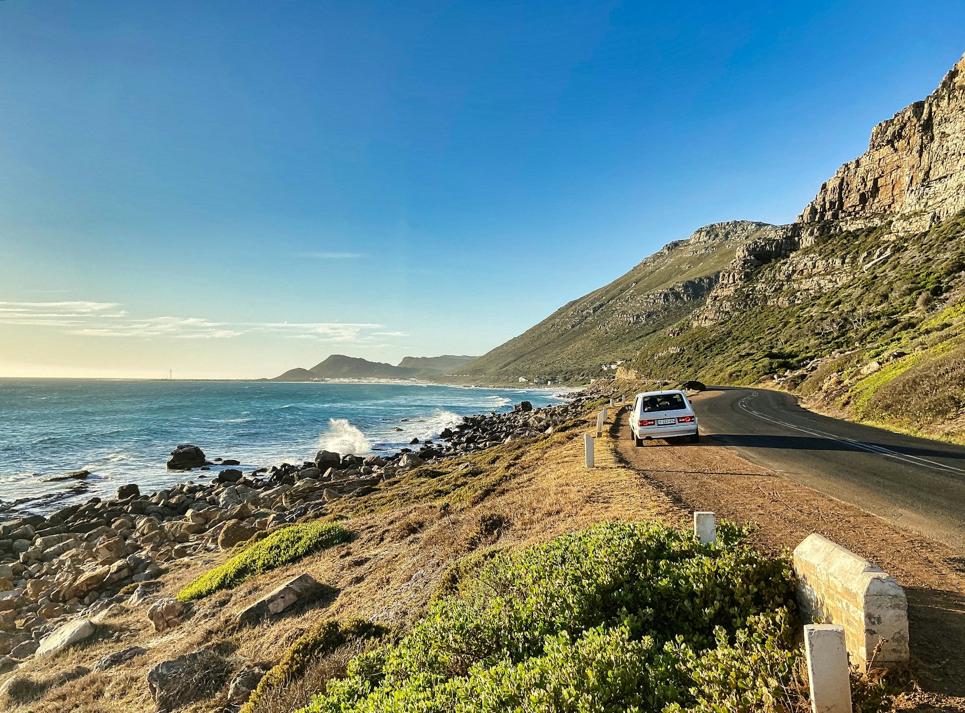 white car on road near body of water during daytime.